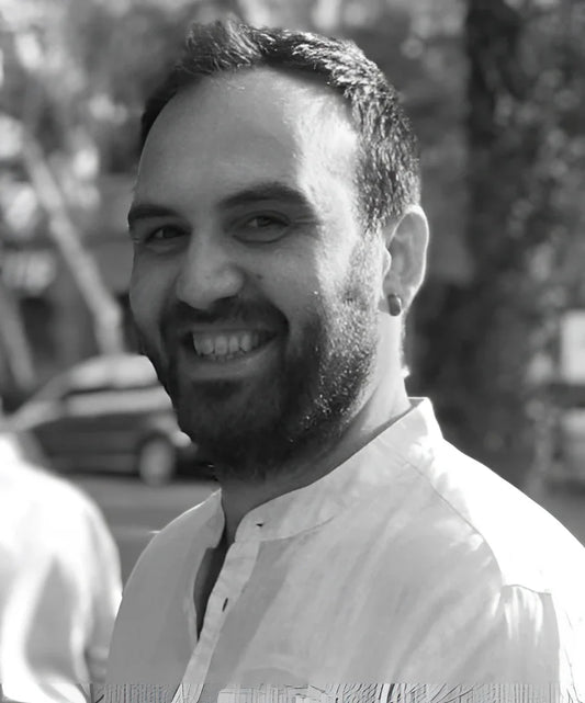 Uomo sorridente con capelli corti scuri e barba in camicia chiara per servizio consulenza restauro dario arredamento vintage